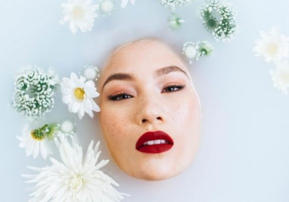 a woman taking a bath with flowers in the water. Only her face is visible.