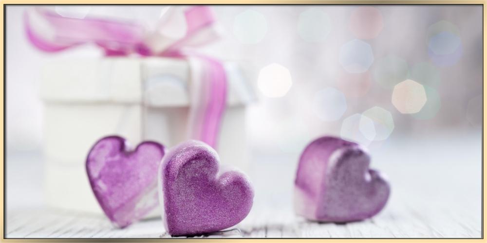 A white gift box with purple ribbon and small heart-shaped ornaments in purple on a white background