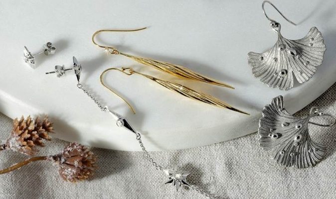 ARY DPO jewelry on a white marble and grey tablecloth surrounded by the holiday cone ornaments