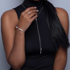 Urban Marquise Y Slider Necklace in silver with white Swarovski crystals on a model with dark skin and black long hair wearing black turtleneck sleeveless top