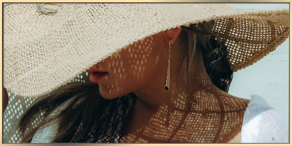 A woman is wearing a summer hat and arydpo earrings