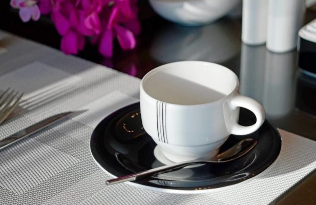 white coffee cup with black plate and spoon set on a table