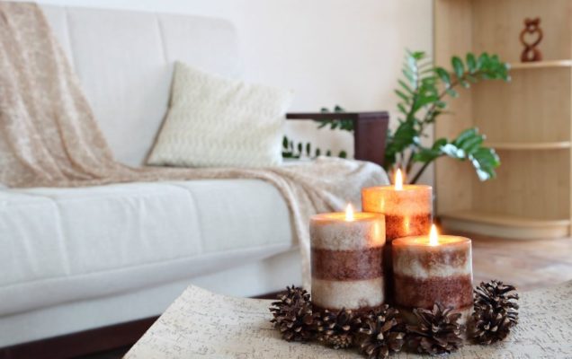 Home decoration with holiday candles and pinecones next to a white couch