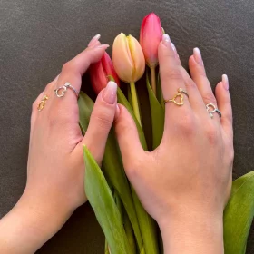 Ladies delicate hands hugging red tulips and she wears multiple 18K Gold vermeil over 0.925 Sterling Silver open resizable ring with white CZ in a Twisted Orb