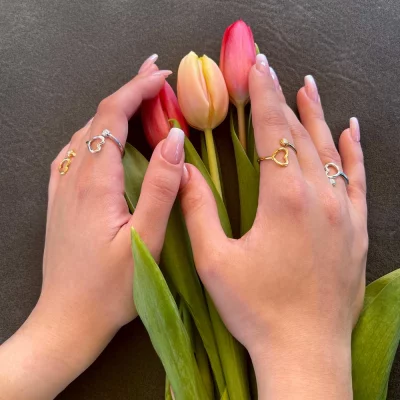 Ladies delicate hands hugging red tulips and she wears multiple 18K Gold vermeil over 0.925 Sterling Silver open resizable ring with white CZ in a Twisted Orb